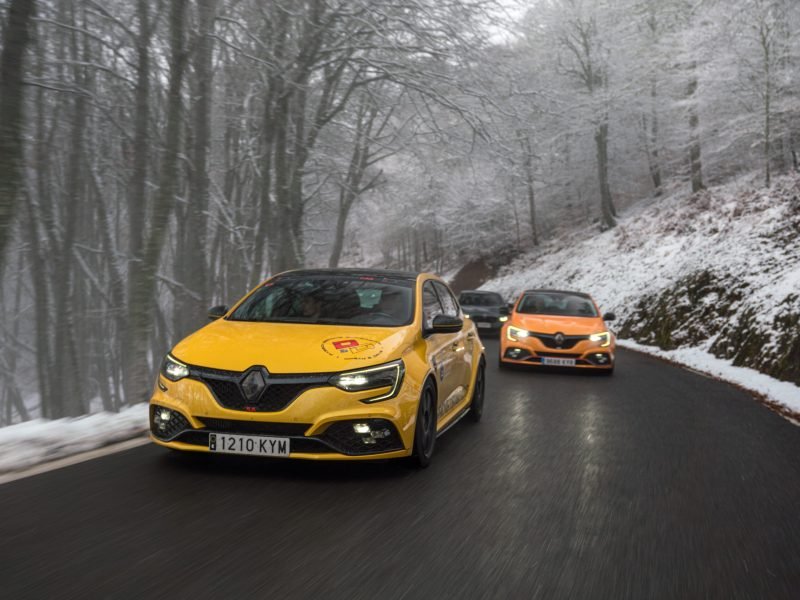 Dos Renault Mégane RS, uno amarillo y otro naranja, por una carretera de bosque nevado