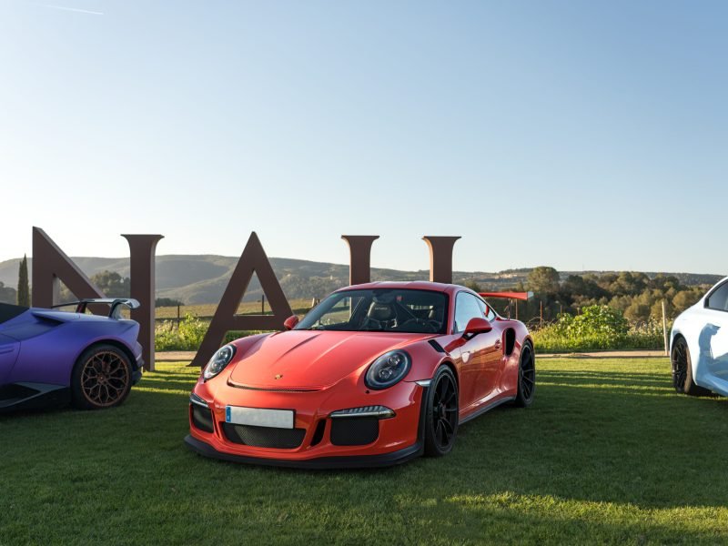 Porsche 911 GT3 RS naranja aparcado en el césped junto a las letras de Vilarnau