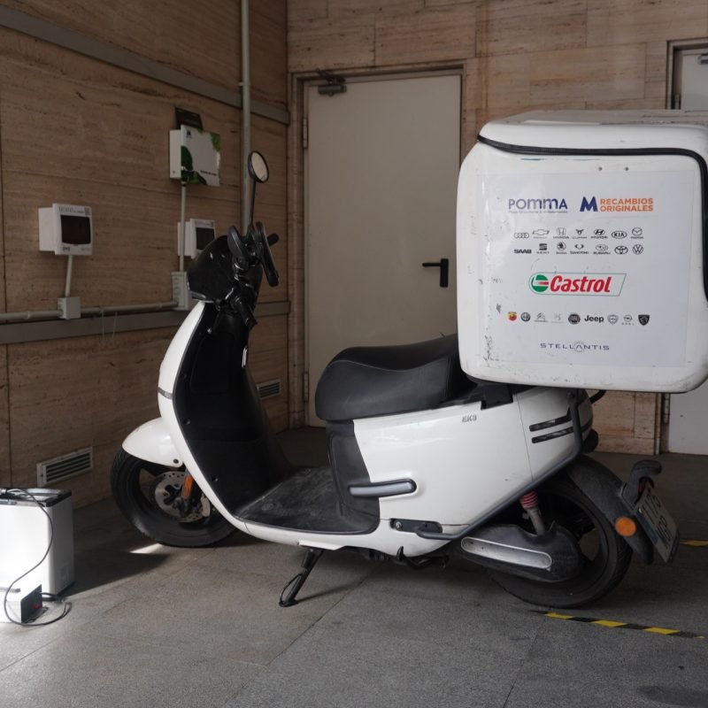 Moto eléctrica de reparto de M Automoción con el baúl rotulado con Castrol y Recambios Originales