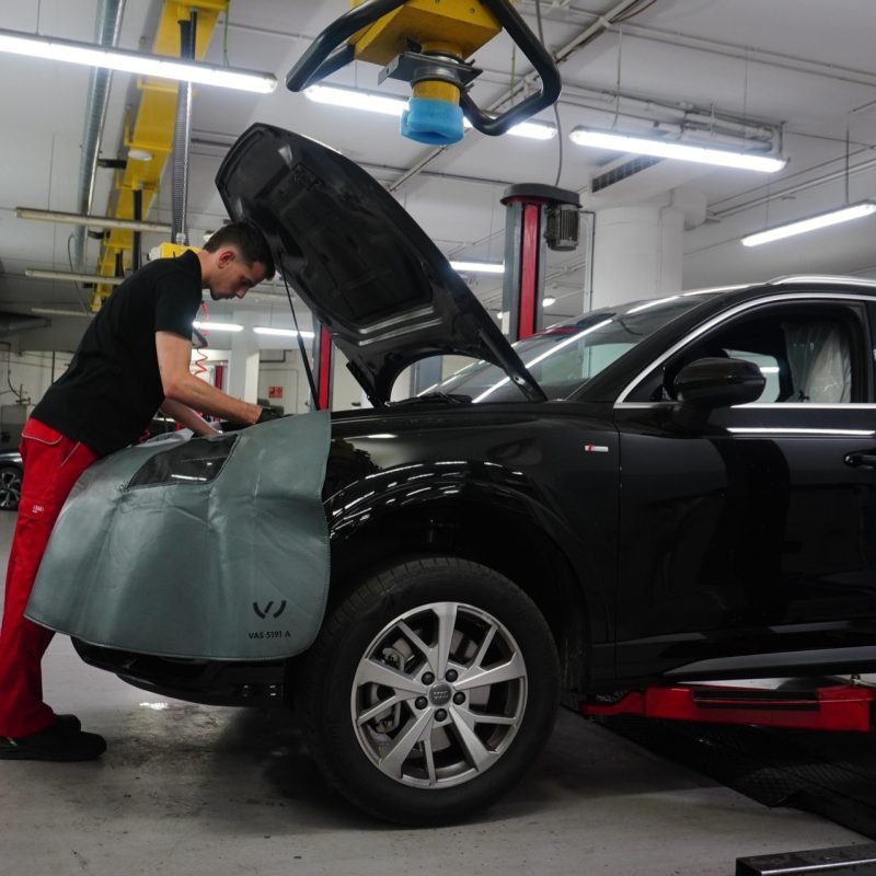 Mecánico de M Automoción revisando el motor de un Audi negro sobre el elevador del taller